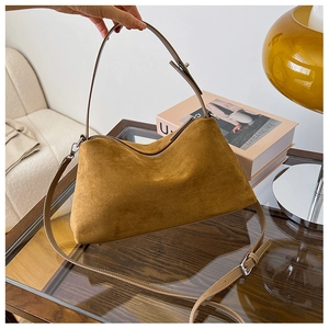 Detail of adjustable leather strap and brown suede texture on a vintage tote bag