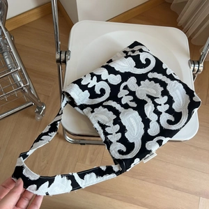 Detail of white floral embroidery on a black cotton linen shoulder bag with a woven tag