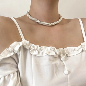 Close-up of a multi-strand twisted pearl choker necklace on a white ruffled shirt