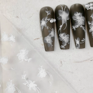 Matte dark taupe nail stickers with white floral patterns and 3D pearl accents
