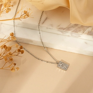 Silver rectangle hammered pendant necklace with thin chain on marble and silk background