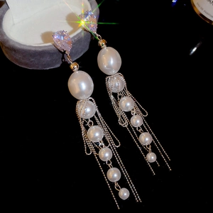 Détail de longues boucles d'oreilles perles avec zircons poire sur fond noir