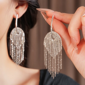 Détail de boucles d'oreilles argentées avec strass brillants et longues chaînes fines