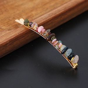 Detailed close-up of golden metal hair clip featuring colorful polished crystal stones