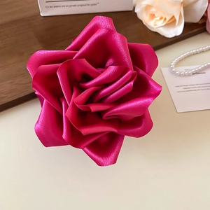 Gros plan sur la pince à cheveux rose en satin rouge vif sur un plateau en bois