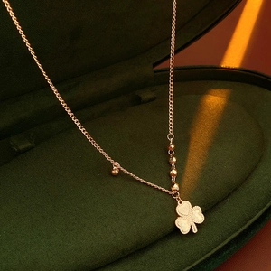 Close-up of rose gold clover pendant necklace with 520 engraving on green velvet