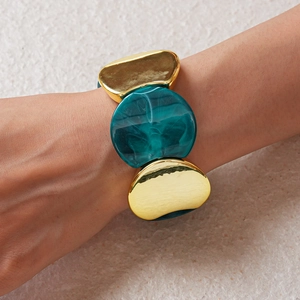 Dettaglio di un bracciale chunky in acrilico e metallo dorato indossato sul polso