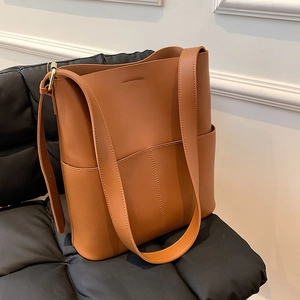 Detailansicht der braunen Leder-Eimertasche auf schwarzem Steppstuhl mit Minimal-Nähten