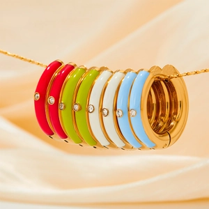 Colorful enamel hoop earrings with zircon stones on a gold chain over champagne silk