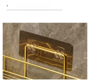 Close-up of golden bathroom shelf with adhesive hooks on marble wall for easy installation