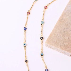 Gold-plated Evil Eye chain necklace with colorful enamel charms on a stone display