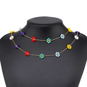 Double-layer gold necklace with colorful handmade beaded flowers on a black jewelry bust