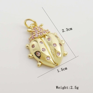 Macro shot of gold ladybug pendant with pink zircon and dimensions 1.5cm x 2.3cm