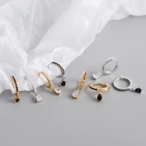 Close-up of teardrop zirconia earrings with pave diamond huggie hoops in gold and silver