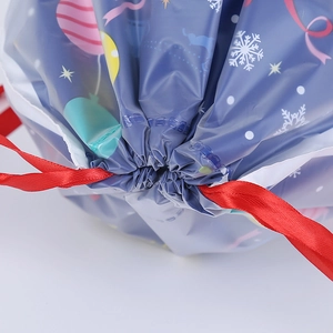 Detail of blue Christmas gift bag with snowflake patterns and red satin drawstring texture