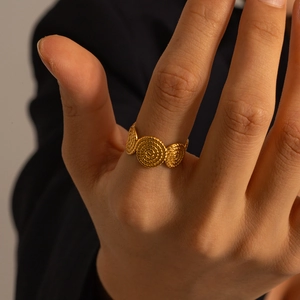 Detail of vintage gold-finished triple spiral ring showing textured metallic swirls on finger