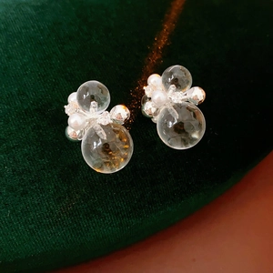 Detailed view of silver zircon pearl earrings with clear spheres on green velvet background