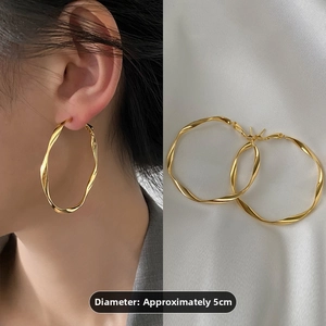 5cm gold twisted wave hoop earrings shown on model and white silk background detail