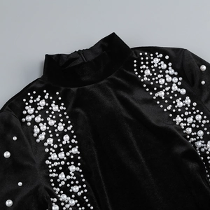 Détails d'une robe en velours noir à col montant avec perles et fermeture à glissière