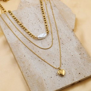 Macro shot of 18k gold triple-layered necklace with baroque pearl and heart pendant