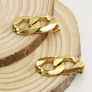 Detailed view of polished 18K gold plated Cuban chain link earrings on wooden surface