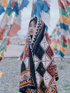Detailed view of bohemian shawl with geometric patterns against colorful prayer flags background