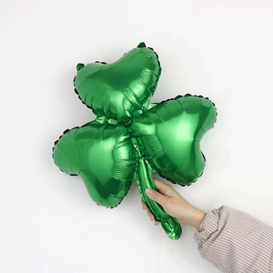 Macro shot of a green four-leaf clover foil balloon held in hand against white background