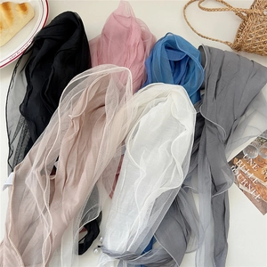 Macro detail of multi-color lace scarves with pearl accents and wavy hem on beige background