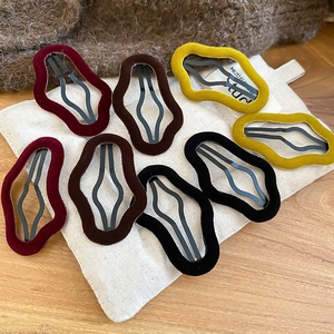 Detail showing wavy velvet hair clips in burgundy and brown on a soft fabric base