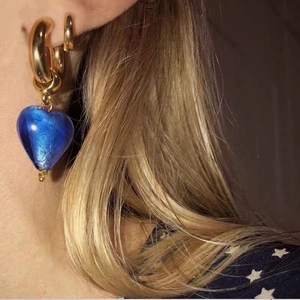 Detailed view of vintage French gold hoop earrings with translucent blue glass heart charm
