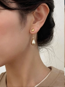 Detailed close-up of vintage golden drop pearl earrings worn by a model in soft lighting
