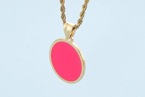 Detailed close-up of a golden rope chain necklace with a pink round pendant
