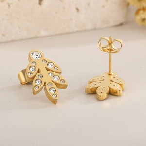Macro shot of gold leaf earrings with sparkling rhinestones on a stone background