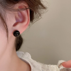 Close-up of minimalist black spherical stud earrings worn by a model for daily wear