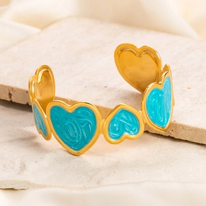 Detail of 18K gold-plated bangle featuring blue enamel hearts with marble texture
