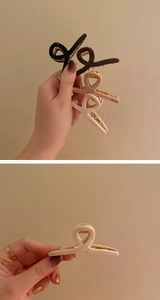 Three minimalist hair claws in black, brown, and beige with gold metal springs