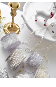 Detailed view of white pearl beads and faceted acrylic crystals on spools for DIY decor