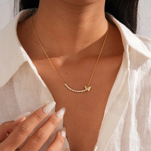 Close-up of 18k gold plated necklace featuring a zircon butterfly and elegant pearls