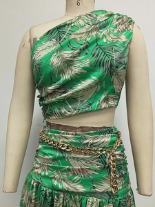 Detail of tropical print two-piece dress with gold chain belt and one-shoulder crop top