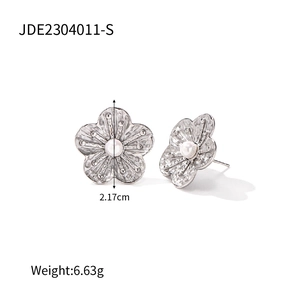 Macro shot of silver flower earrings with white pearl center and petal textures