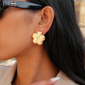Detailed view of gold five-petal flower stud earrings with polished mirror finish effect