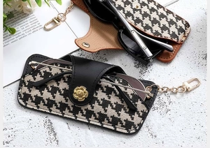 Detail of houndstooth glasses pouch with gold flower clasp and PU leather trim