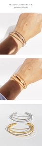 Detail of minimalist triple-layer geometric open cuff bracelet in gold and silver finish