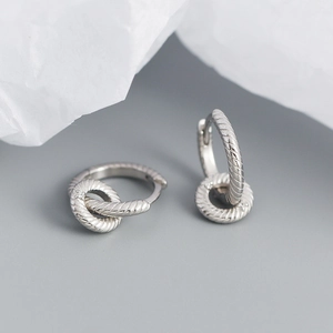 Macro view of interlocking silver twisted hoop earrings with polished metallic texture