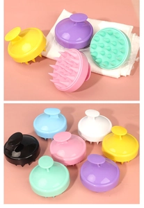 Various colors of silicone scalp massager brushes displayed on a soft towel and pink background
