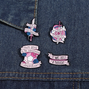 Vue détaillée de quatre badges en émail rose avec citations sur tissu denim bleu