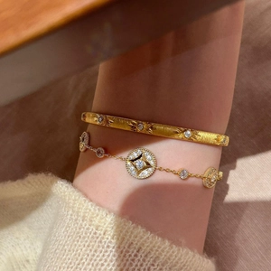 Dettaglio del set bracciale e rigido a stella placcato oro 18K su tessuto caldo