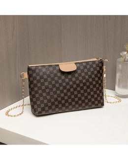 Detail view of vintage printed crossbody bag with golden chain strap and leather trim