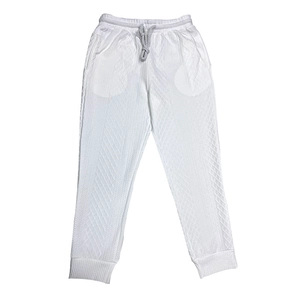 Close-up detail of white knitted trousers showing jacquard diamond texture and drawstring waist