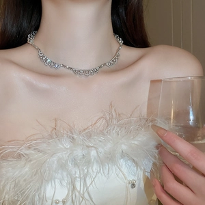 Detail of silver lace necklace with full diamonds worn on the collarbone at a gala